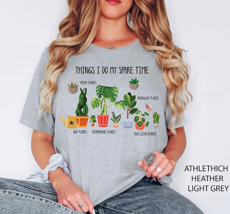 May include: Light grey t-shirt with the text "THINGS I DO MY SPARE TIME" and illustrations of plants. The shirt also has the text "ATHLETHICH HEATHER LIGHT GREY" on the right side.