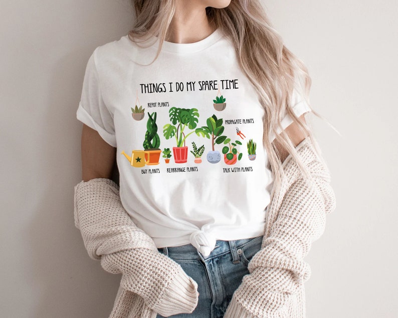 May include: White t-shirt with the text "THINGS I DO MY SPARE TIME" and illustrations of plants. The graphic includes the phrases "REPOT PLANTS", "PROPAGATE PLANTS", "BUY PLANTS", "REARRANGE PLANTS", and "TALK WITH PLANTS".
