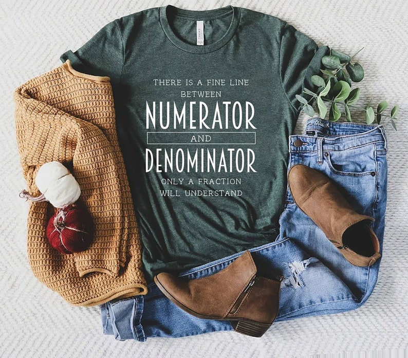 May include: Dark green t-shirt with the text "THERE IS A FINE LINE BETWEEN NUMERATOR AND DENOMINATOR ONLY A FRACTION WILL UNDERSTAND" in white. The shirt is paired with blue jeans, brown boots, and a tan sweater.