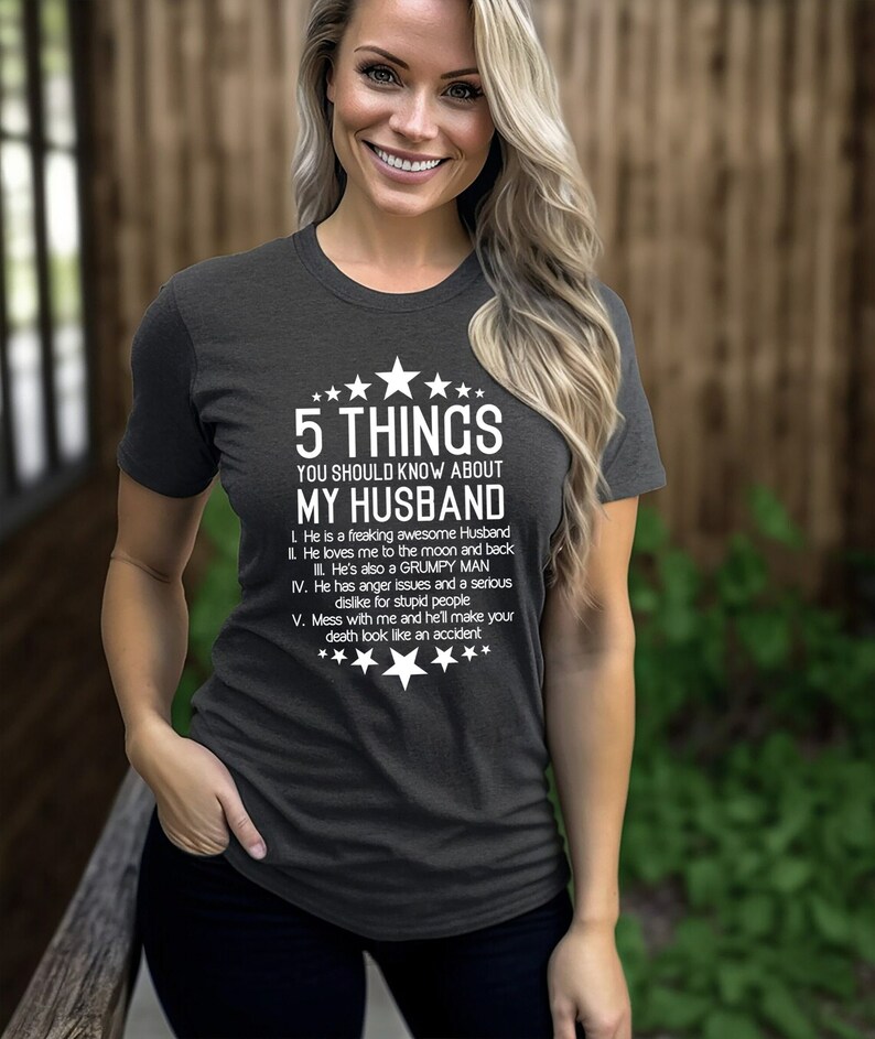 May include: Dark gray t-shirt with the text "5 THINGS YOU SHOULD KNOW ABOUT MY HUSBAND" in white. The text is accompanied by star graphics. The shirt lists five humorous facts about a husband.