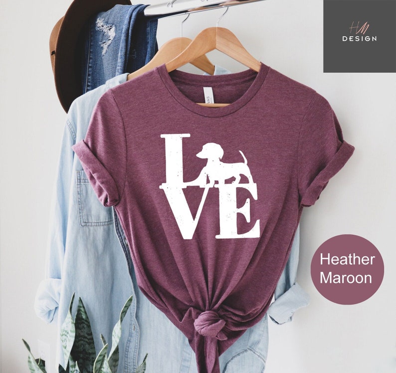May include: A heather maroon t-shirt with a white graphic of the word "LOVE" with a dachshund silhouette replacing the "O".