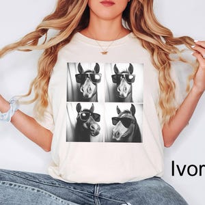 May include: A white t-shirt with a black and white image of four horses wearing sunglasses. The horses are arranged in a grid pattern. The text "Ivory" is visible in the bottom right corner of the image.