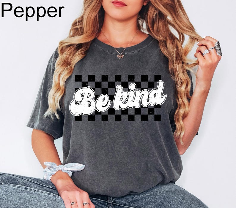 Pu&ograve; includere: Una t-shirt a maniche corte grigio antracite con una grafica rettangolare a scacchi bianchi e neri e la scritta Be kind in un carattere bianco in stile retr&ograve;. La maglietta presenta un girocollo e una texture del tessuto slavata.