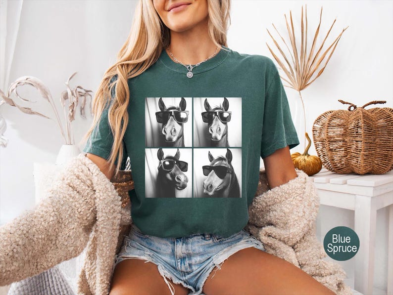 May include: A teal green t-shirt with a black and white image of four horses wearing sunglasses. Each horse has a different expression.