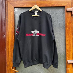 May include: Black sweatshirt with a white embroidered design of the Brandenburg Gate and the text "Berlin Marathon".