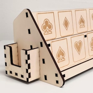 Könnte beinhalten: Ein hölzerner Spielkarten-Präsentationsständer mit zwei Reihen von Kartenfächern. Jedes Fach zeigt ein anderes Spielkartenzeichen: Kreuz, Karo, Pik und Herz. Der Ständer ist aus hellem Holz gefertigt und hat ein schräges Design.