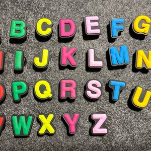 May include: A set of colorful alphabet letter tiles in various colors, including red, green, yellow, pink, blue, and black. The letters are arranged in alphabetical order.