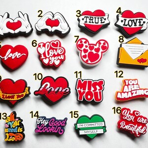 May include: A set of 16 colorful shoe charms featuring hearts, love-themed messages, and other designs. The charms are made of rubber and have a variety of colors, including red, white, yellow, green, and pink.