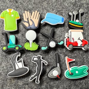 May include: A collection of colorful golf-themed charms. The charms include a green polo shirt, golf gloves, a blue visor, golf clubs, a golf cart, a golf ball on a tee, and golfer silhouettes.