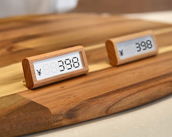 May include: Two wooden price tags with digital displays showing the price in Japanese Yen. The tags are on a wooden surface.