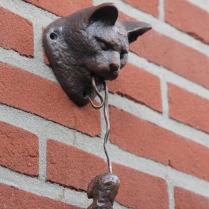 May include: A cast iron cat door knocker with a small, dangling, cast iron figure attached to a metal chain.