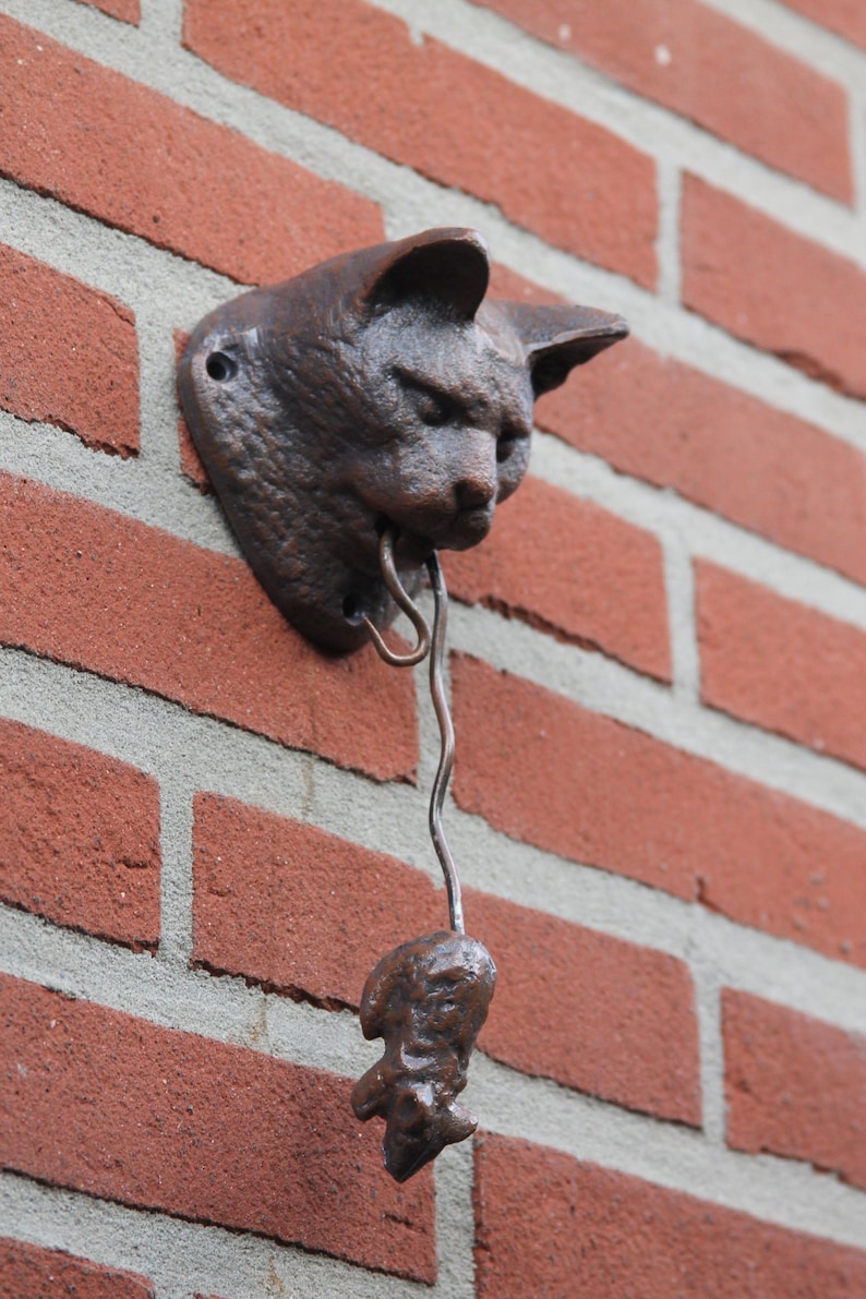 May include: A cast iron cat door knocker with a small, dangling, cast iron figure attached to a metal chain.