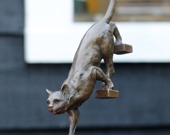 una escultura de bronce de un gato bajando las escaleras