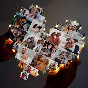 May include: A heart-shaped photo collage with a string of lights around the edges. The collage is made up of many small photos of couples, some of whom are holding hands, hugging, or kissing. The photos are arranged in a random pattern.