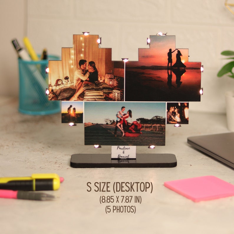 May include: A heart-shaped photo frame with five photos of a couple. The frame is made of wood and has a black base. The frame is lit up with small white lights. The frame is 8.85 inches wide and 7.87 inches tall. The text "Pauline & Daniel" is written on the base of the frame.