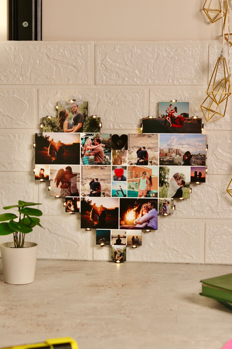 May include: A heart-shaped photo collage with lights, featuring a couple in various settings. The collage is made up of 25 individual photos, each with a small light bulb.