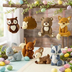 May include: A collection of felt woodland animal ornaments, including an owl, hedgehog, bear, fox, bunny, squirrel, deer, and raccoon. The ornaments are brown, tan, gray, and white, with colorful Easter eggs and greenery. The ornaments hang from a branch.