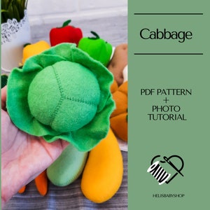 Op de afbeelding: Een groene viltkool met een groene viltbuitenlaag. De kool wordt in een hand gehouden. De afbeelding bevat de tekst "Cabbage", "PDF Pattern + Photo Tutorial" en "Helisbabyshop".