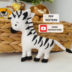 May include: A white and black zebra plush toy with black hooves. The zebra is sitting in a wicker basket. The image also includes text that says "PDF PATTERN" and "VIDEO INSTRUCTION".