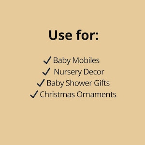 May include: A tan background with black text that reads "Use for:" followed by a list of items. The list includes "Baby Mobiles", "Nursery Decor", "Baby Shower Gifts", and "Christmas Ornaments". Each item is preceded by a green checkmark.