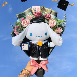 May include: A graduation bouquet featuring a plush white character wearing a graduation gown and cap, surrounded by pink and red roses, greenery, and a pink bow. Includes a card that says "Congratulations". Graduation caps are tossed in the air.