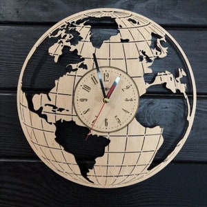 Op de afbeelding: Een houten wandklok in de vorm van een globe met een zwart-witte wereldkaartontwerp. De wijzerplaat van de klok heeft zwarte wijzers en Romeinse cijfers.