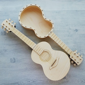 May include: Two wooden guitars, one with a hollow body and the other with a solid body. Both guitars are made of light wood and have a natural finish.