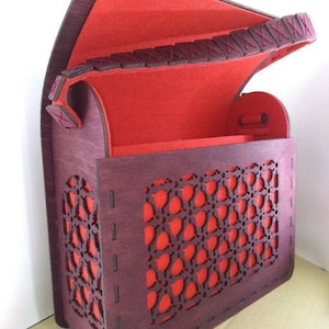 Puede incluir: Una caja de madera con un interior de fieltro rojo y un diseño de celosía decorativo. La caja tiene una tapa con bisagras y una correa de cuero.