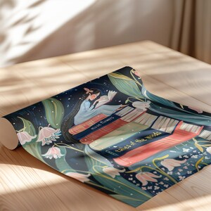 May include: A rolled up wrapping paper design featuring a girl reading a book on a stack of books. The books have titles "Moon Flowers" and "Tales of the Woods". The design is surrounded by flowers and leaves on a dark blue background.