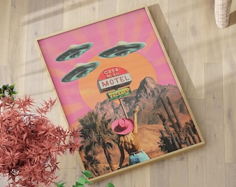 May include: A framed art print featuring a retro-style desert scene with a pink and orange sunset, palm trees, and a motel sign. Three UFOs hover above. A person in a pink hat is reaching towards the sky. The sign reads "Casa del Sol Motel VACANCY."