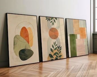 May include: Three framed abstract art prints with geometric shapes and foliage in shades of green, orange, and brown. The prints are displayed on a light wood floor.