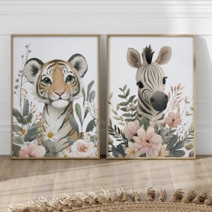 May include: Two framed watercolor prints featuring a tiger cub and a zebra. The tiger has orange and black stripes, surrounded by greenery and flowers. The zebra print has a black and white striped head, also surrounded by flowers.