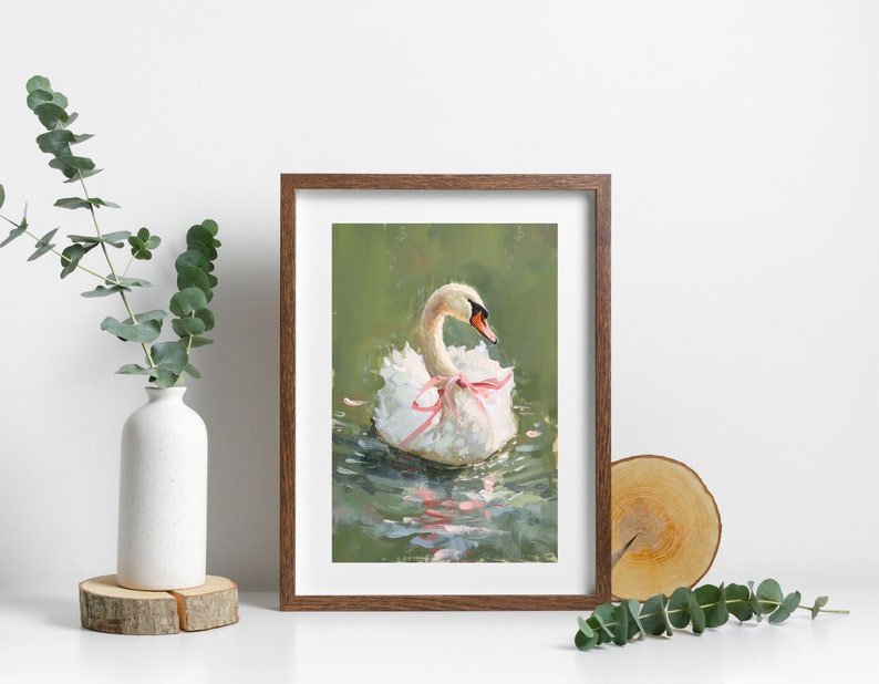May include: A framed painting of a white swan with a pink ribbon around its neck, swimming in a green pond. The swan is facing to the right and the water is reflecting the light.