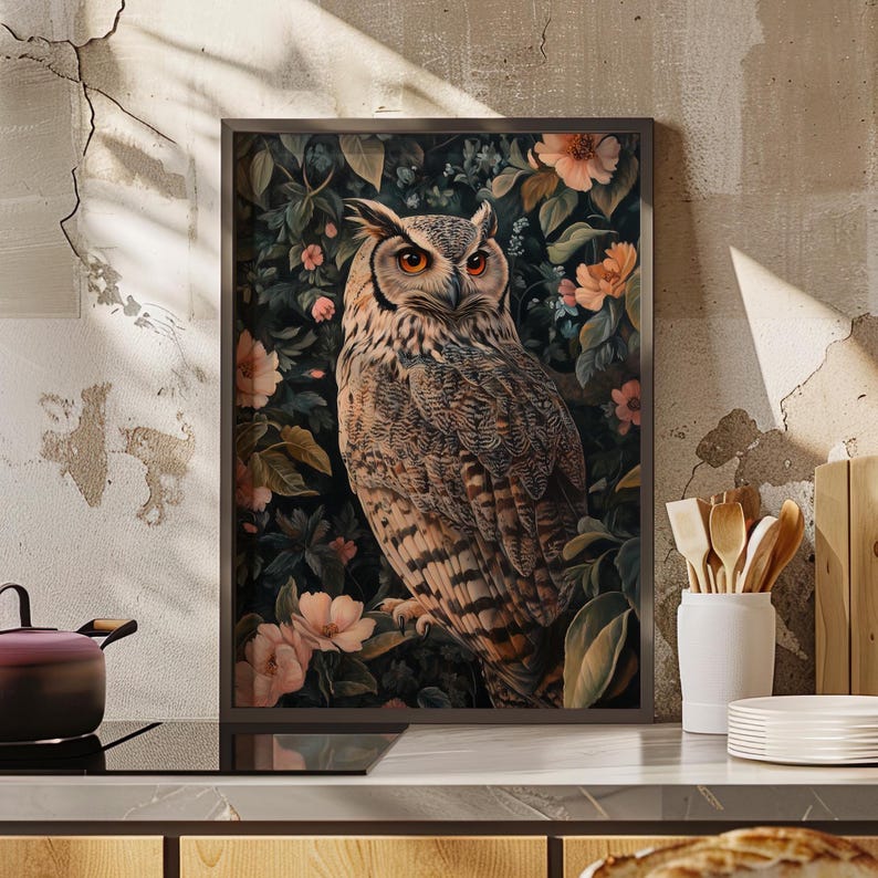 May include: A framed print of a brown and white owl with orange eyes perched in a lush green and pink floral arrangement.