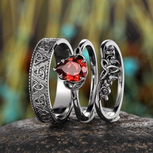 May include: Three silver rings with intricate Celtic knot designs. The center ring features a pear-shaped red gemstone.