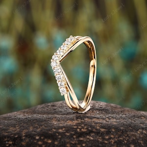 Könnte beinhalten: Ein Goldring mit einem V-förmigen Design, besetzt mit kleinen, klaren Steinen.