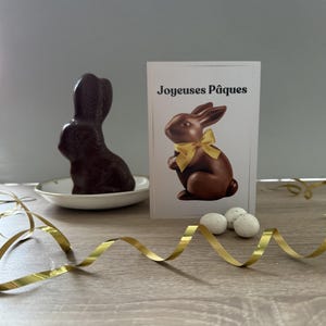 Osterkarte auf Französisch. „Carte de Pâques en Français“. Schoko Osterhase mit goldener Schleife. Lapin de Pâques und Schokolade mit Ruban Doré.