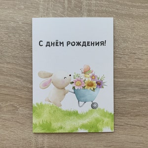 Geburtstagskarte in russischer Sprache. Hase mit einem Rollwagen, der mit Blumen gefüllt ist.                             Das ganze Haus . Handwäsche.