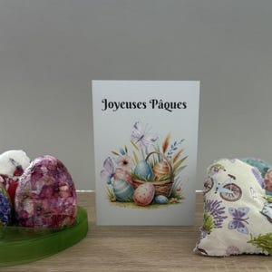 Osterkarte auf Französisch. „Carte de Pâques en Français“. Oeufs de Pâques im Panier und Papillons. Ostereier im Körbchen und Schmetterlinge.