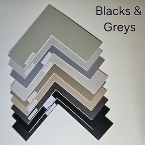 May include: A set of 9 different shades of grey and black cardstock paper samples. The samples are arranged in a fan shape, with the lightest shade at the top and the darkest shade at the bottom. The text "Blacks & Greys" is written in white letters on a black background at the top of the image.
