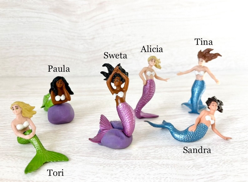 Puede incluir: Un conjunto de diez figuras de sirenas, cada una con una cola y un cabello de color diferente. Las sirenas se llaman: Tori, Paula, Sweta, Alicia, Tina, Sandra.