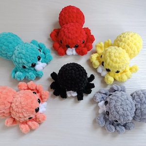 May include: Six crocheted octopus plushies in different colors, including red, blue, yellow, black, pink, and gray. Each octopus has a white crocheted mouth and eyes.