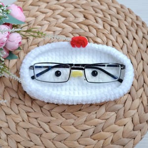 Puede incluir: Estuche para gafas de crochet blanco con forma de pollo, con cresta roja y pico amarillo. El estuche contiene un par de gafas.