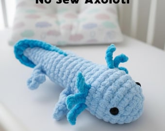 May include: A light blue crocheted axolotl plush toy with darker blue external gills and a long tail. The plush features black plastic safety eyes and a textured yarn surface. The text No Sew Axolotl is visible above the toy.