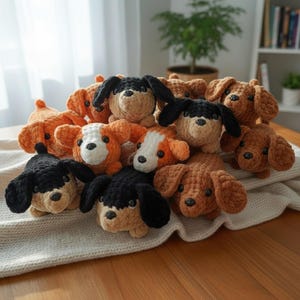 May include: A collection of handmade crochet dog toys in various colors, including black, brown, and orange. The plush dogs have floppy ears and button eyes, resting on a cream-colored blanket. The toys are arranged in a pile.