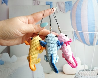 Peut inclure: Trois peluches axolotl en crochet avec des porte-clés. Les axolotls sont jaunes, bleus et roses.