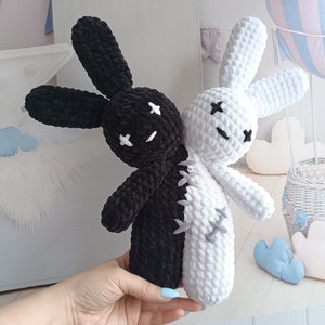 Pode incluir: Um coelho de pel&uacute;cia de croch&ecirc; feito &agrave; m&atilde;o, dividido verticalmente em preto e branco. O coelho tem orelhas compridas, olhos costurados e boca costurada. As duas metades s&atilde;o costuradas com fio cinza. O brinquedo &eacute; segurado por uma pessoa.