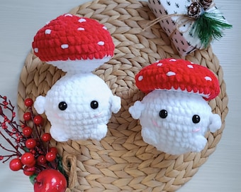 May include: Two crocheted mushroom plushies with white bodies and red and white mushroom caps. The plushies are sitting on a woven wicker surface.
