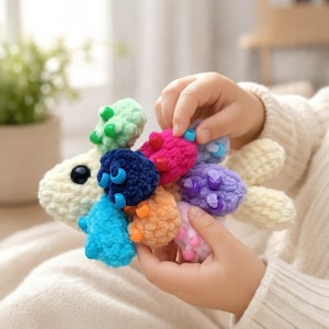 May include: A plush toy shaped like a fish with a cream-colored body and a mane of multi-colored, textured, fuzzy segments in shades of green, dark blue, bright blue, orange, pink, purple, and light blue, each accented with small beads.