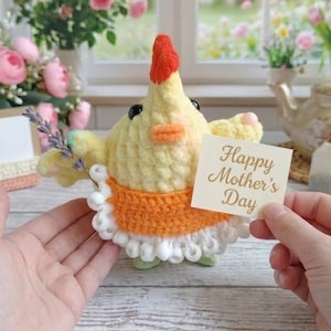 May include: A handmade yellow crochet chick with an orange apron and a red comb. The chick holds a sprig of lavender and a card that reads "Happy Mother's Day". The chick has black eyes and a small orange beak.